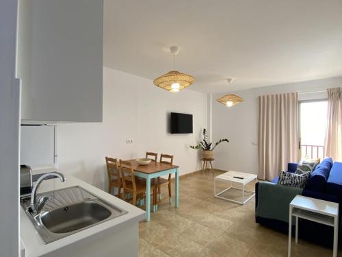 eine Küche und ein Wohnzimmer mit einem Sofa und einem Tisch in der Unterkunft Vivienda vacacional sur de europa b 3 4 in La Restinga