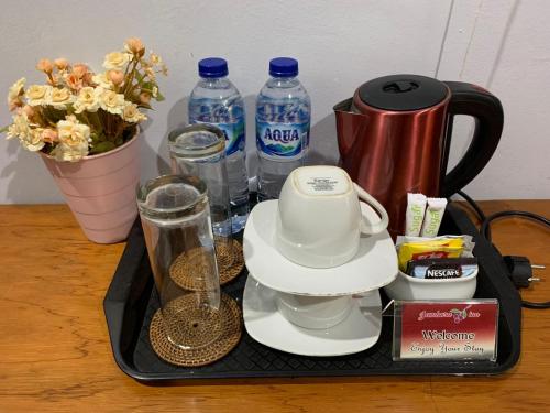 a tray with a tea kettle and cups and water bottles at Jambura Inn in Gorontalo