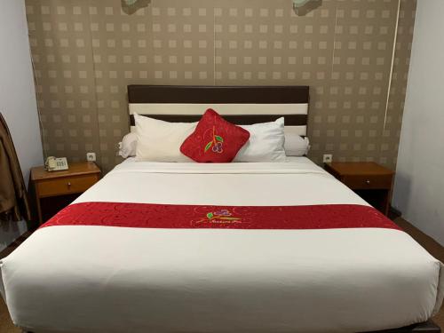 a bedroom with a large white bed with red pillows at Jambura Inn in Gorontalo
