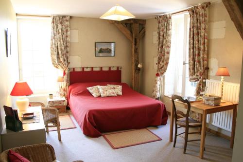 sypialnia z czerwonym łóżkiem, stołem i krzesłami w obiekcie Le Moulin de Montrésor w mieście Montrésor
