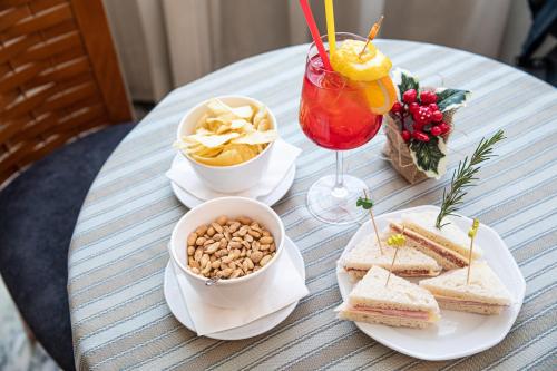 a table topped with sandwiches and chips and a drink at Hotel Vittoria in Sondrio
