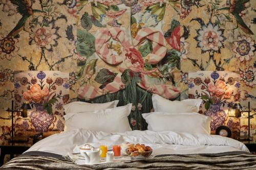 a bedroom with a bed with a floral wall at Hotel du Petit Moulin in Paris