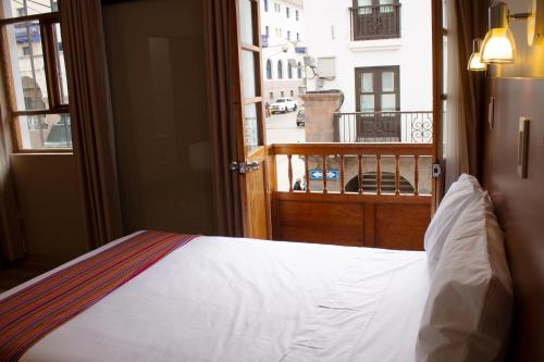a bedroom with a bed and a view of a balcony at Hotel San Pedro Plaza in Cusco