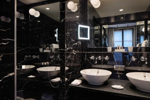 a bathroom with four sinks in a black wall at Le Pavillon de la Reine & Spa, Place des Vosges in Paris
