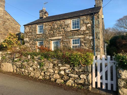 an old stone house with a white fence at Beautiful Cottage near Harlech with ocean views in Llanfair