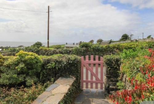 a pink gate in a garden with flowers at Beautiful Cottage near Harlech with ocean views in Llanfair
