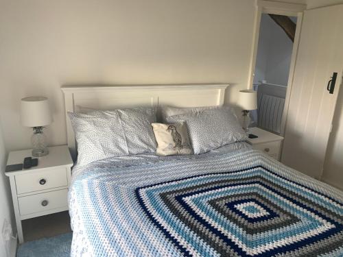 um quarto com uma cama com um cobertor azul e branco em Beautiful Cottage in Llanfair with ocean views em Llanfair