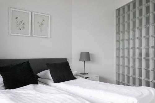 a bedroom with a bed with white sheets and black pillows at 2ndhomes Apartment in Kamppi Center with Sauna and Balcony in Helsinki