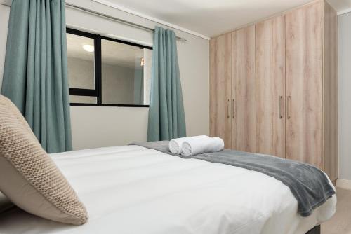 a bedroom with a white bed with green curtains at Waters Edge Apartments in Cape Town