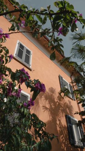 a building with three windows and purple flowers at Stalder Meat & Bed in Muralto
