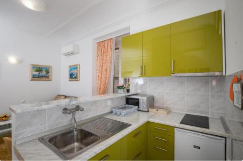 a kitchen with green cabinets and a sink at Anima Mea Apartment in Dubrovnik