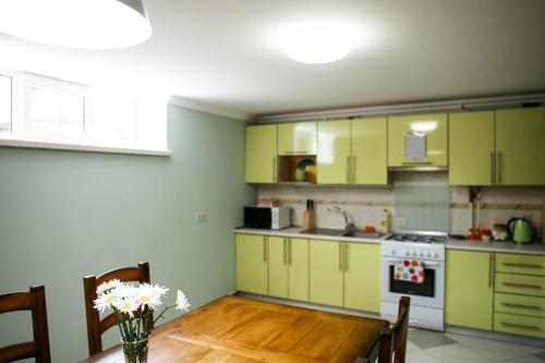 a kitchen with green cabinets and a wooden table at Sweet Home Hostel in Chernivtsi