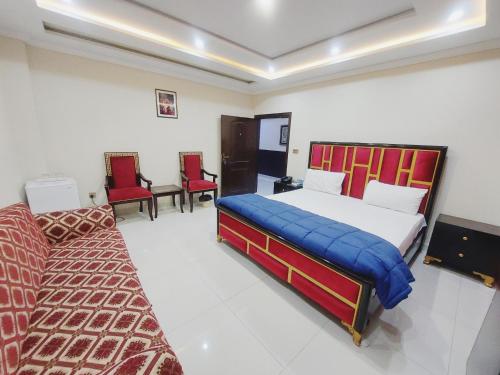 a bedroom with two beds and two red chairs at Hotel White Pearl in Lahore