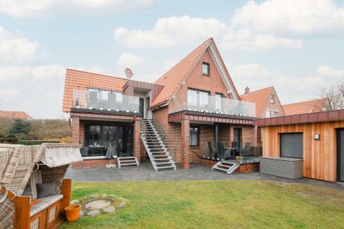 a brick house with a deck and a patio at Winkelschiffchen IV mit Sauna in Juist