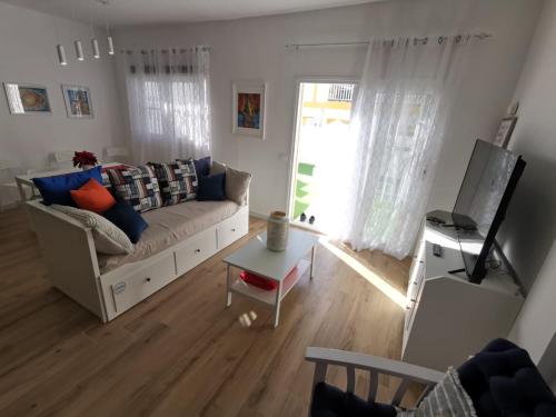 a living room with a couch and a table and a tv at Villa Megila in Caleta De Fuste