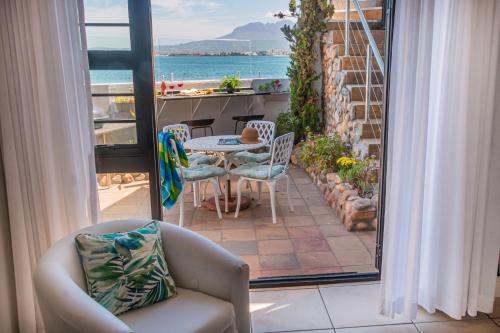 a patio with a table and chairs on a balcony at 185 on BEACH Boutique Suites in Gordonʼs Bay