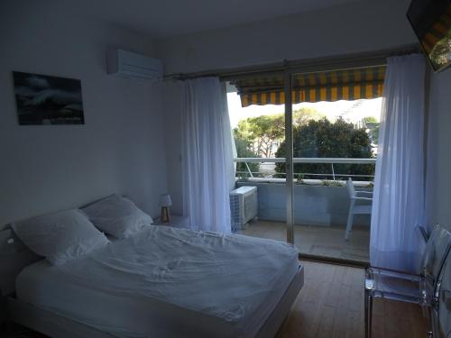 une chambre avec un lit et une vue sur un balcon dans l'établissement Appartement bord de mer Marina Baie des Anges, à Villeneuve-Loubet