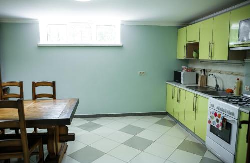 a kitchen with green cabinets and a table and a stove at Sweet Home Hostel in Chernivtsi