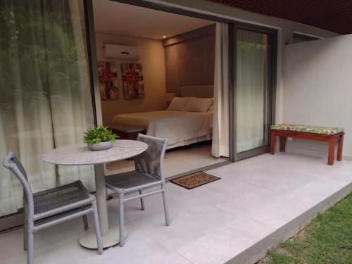 1 dormitorio y patio con mesa y sillas. en FLAT NA PRINCIPAL DE PIPA en Pipa