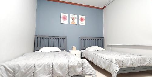 2 camas en un dormitorio con paredes azules en Healinghouse Peakjang, en Buyeo