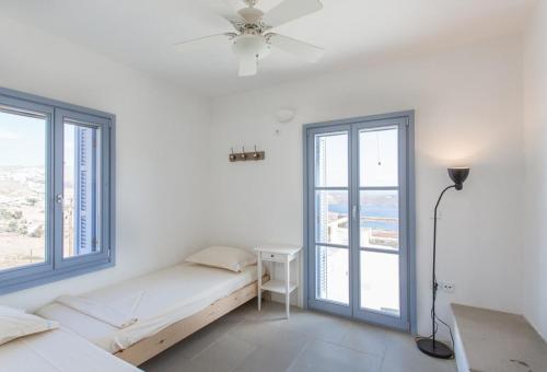 ein weißes Zimmer mit einem Bett und zwei Fenstern in der Unterkunft Serifos Stone Villa B in Rámos