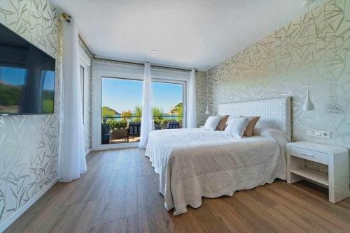 a white bedroom with a bed and a large window at La Concha Beach Deluxe in San Sebasti&aacute;n