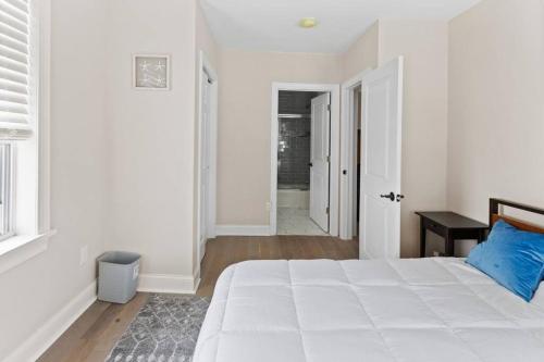 a white bedroom with a large white bed with a blue pillow at Renovated Beach Block 7BR North Beach Atlantic City - Steps to Beach & Casino in Atlantic City