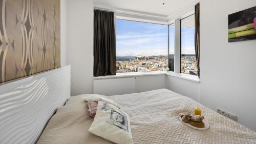 ein Schlafzimmer mit einem Bett und einem großen Fenster in der Unterkunft Panorama - Sunset and castle view, 22nd floor, garage, AC in Bratislava