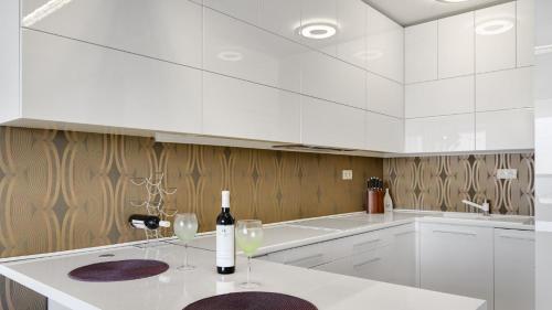 eine weiße Küche mit zwei Gläsern Wein auf der Theke in der Unterkunft Panorama - Sunset and castle view, 22nd floor, garage, AC in Bratislava