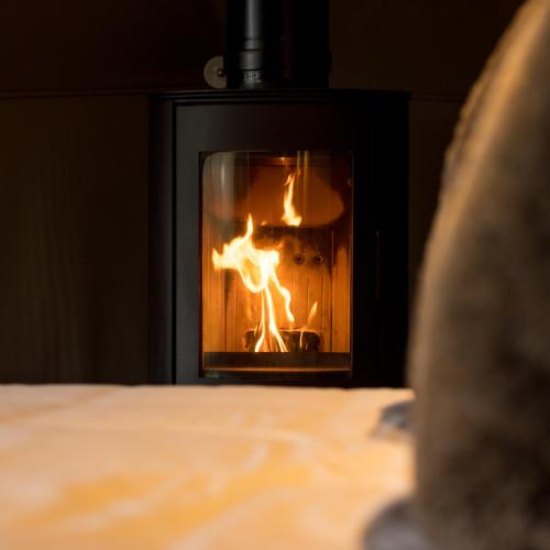 a fire in a fireplace with a person in front at Luna Domes in Chiddingstone