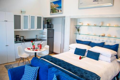 a bedroom with a large bed and a blue couch at 185 on BEACH Boutique Suites in Gordonʼs Bay