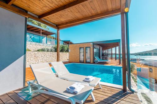 a house with a swimming pool and a deck with a chair at Olivia Green Camping in Tisno