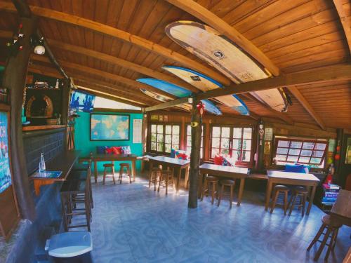 a restaurant with tables and chairs and a ceiling with surfboards at Haleakala Hostel & Pousada in Praia do Rosa
