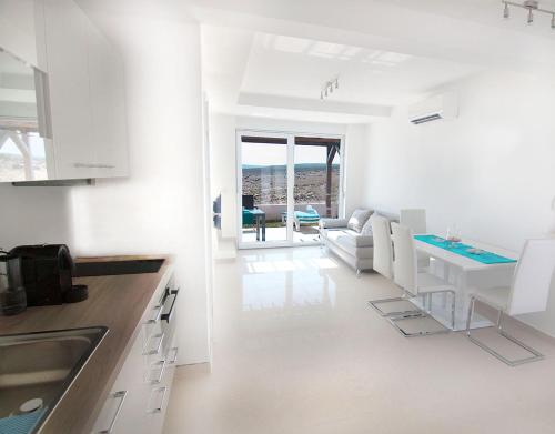 uma cozinha branca e sala de estar com mesa em Atrium Blue Holiday House em Ražanac