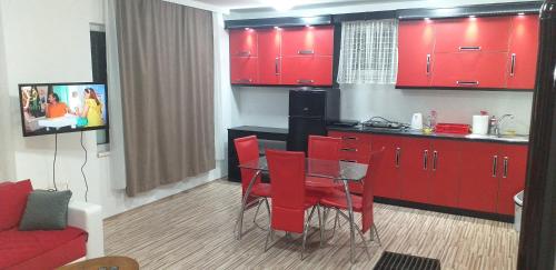 a kitchen with red cabinets and a table with red chairs at Apartmani Grza in Paraćin