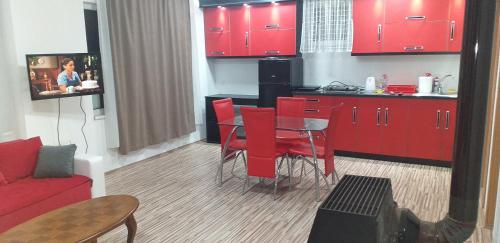 a kitchen with red cabinets and a table and red chairs at Apartmani Grza in Paraćin