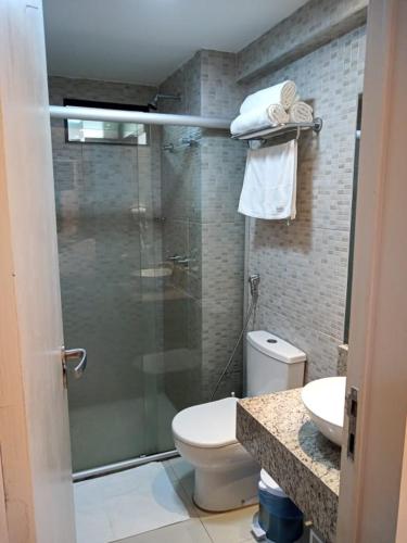 a bathroom with a toilet and a glass shower at Tabatinga Residence Service - Flat 02 in Jacumã