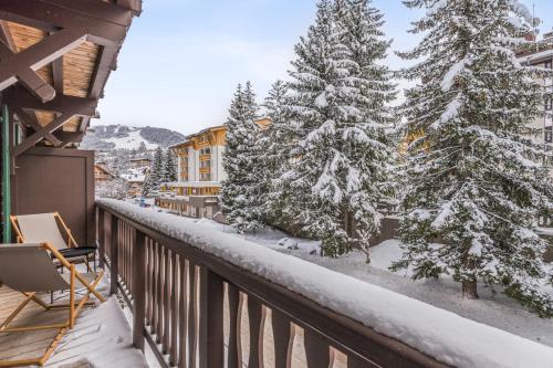 - un balcon avec des arbres enneigés et un bâtiment dans l'établissement Studio Cristallin - Welkeys, à Megève