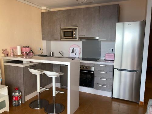 kuchnia z lodówką i stołkami ze stali nierdzewnej w obiekcie epsylon 2 w Almuñécar