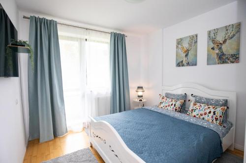 Un dormitorio con una cama con sábanas azules y una ventana. en Apartament Maza, en Sinaia