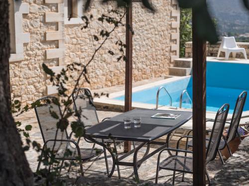 a table and chairs next to a swimming pool at Koules Estate, simplicity & natural, By ThinkVilla in Argoulión