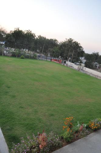a large green field with flowers in a park at Pride Biznotel Manjusar Vadodara Near Sokhda Lake in Vadodara