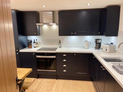 a kitchen with black cabinets and white counter tops at Smithy House in Tongue