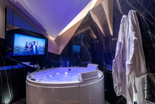 a bathroom with a tub and a tv on the wall at Le Suites Del Duomo Luxury in Catania