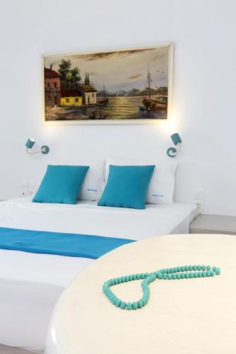 two beds with blue pillows and a painting on the wall at Church and Cave - Santorini Private Residences in Mesaria