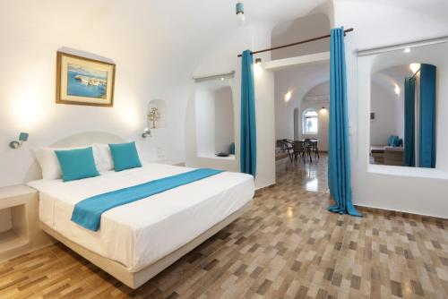 a bedroom with a large white bed and blue curtains at Church and Cave - Santorini Private Residences in Mesaria
