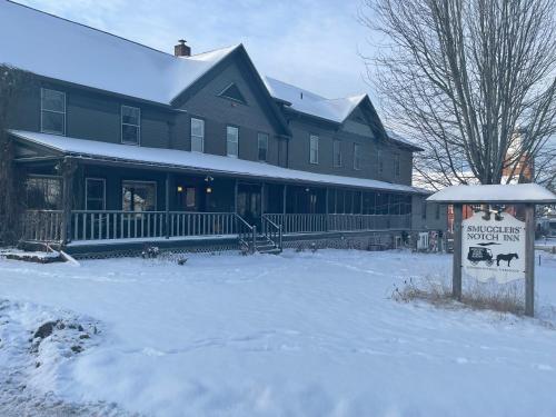 a large house with a sign in the snow at Smugglers Notch Inn in Jeffersonville
