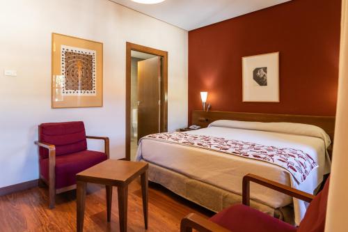 een hotelkamer met een bed en een stoel bij Hospedería Valle del Ambroz in Hervás