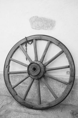 a wooden wagon wheel sitting next to a wall at El Robledillo in Robledillo