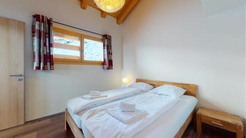 a bedroom with a bed with white sheets and a window at Modern chalet surrounded by nature in Vercorin in Vercorin